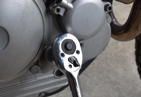 ヤマハのオフロードバイクのセロー250のエンジンにあるオイル注入口のボルトをソケットレンチで締結する様子