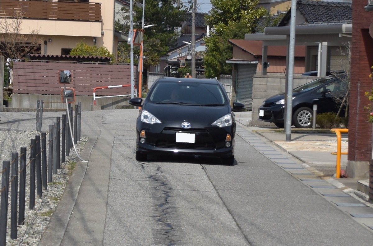 住宅街の道路の真ん中を走る車 あおぶさモーターサイクル