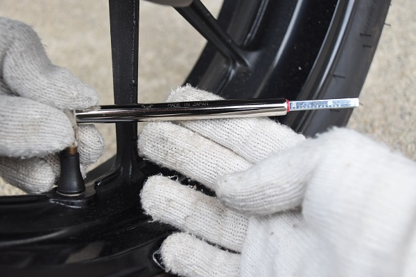 バー式タイヤゲージでバイクのタイヤの空気圧を測定している様子
